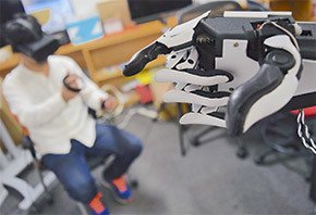 図3　左：Fusionの操作をしているサライジ氏　右：ロボットハンドで自分を指さす